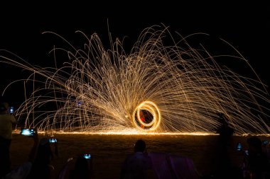 Dansçı gösterisi Tayland 'da barın ve restoranın yakınındaki partide plajda çelik yünün ateşini yüzdürüyor.