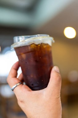 Kahve dükkanında elinde buzlu kahve tutan bir adam.