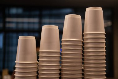 Kahve makinesinin üstünde sıraya dizilmiş sıcak içecek için beyaz kağıt kahve fincanı.