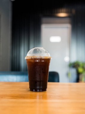 Ahşap masada şeffaf plastik kahve.