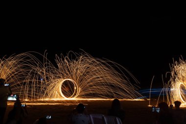 Dansçı gösterisi Tayland 'da barın ve restoranın yakınındaki partide plajda çelik yünün ateşini yüzdürüyor.
