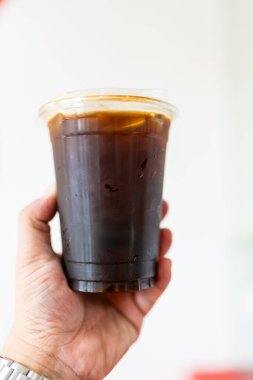 Elinde buzla bir bardak sade kahve.