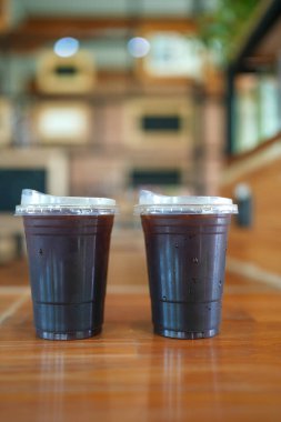 Kahve dükkanındaki ahşap masanın üzerinde iki plastik kahve fincanı.