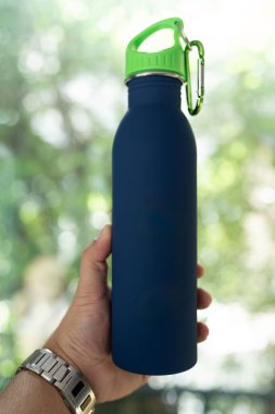 Mavi, yeniden kullanılabilir çelik şişeyi tutan erkek elini kapat.