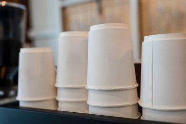 Kahve makinesinin üstünde beyaz kağıt kahve fincanı var.