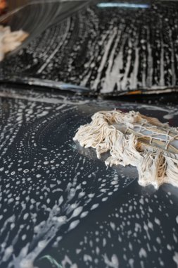 Çamaşır yıkarken arabanın üzerine mafya bezi konmuş. Araba yıkama konsepti