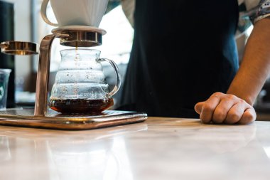 Alternatif kahve demleme metodu, damlatıcı ve kağıt filtresinin üzerine dökülüyor. Barista damlatan kahve yapıyor.