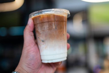 Elinde bir bardak buzlu sütlü kahve tutan adam. Buzlu kahve.