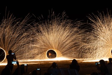 Dancer show swimg the fire of steelwool on the beach in party near bar and restaurant in Thailand clipart