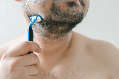 Banyoda sakal tıraşı olan, günlük bakım rutinini yakalayan, kişisel temizlik yapan bir adam..