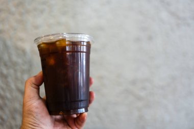 El ele tutuşmuş buzlu kahve ya da Americano kahvesi.