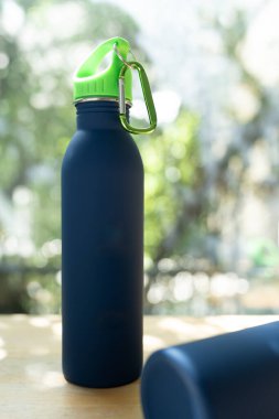 Tam boy mavi su şişesi ahşap masa üzerinde bir doğa arka planına karşı