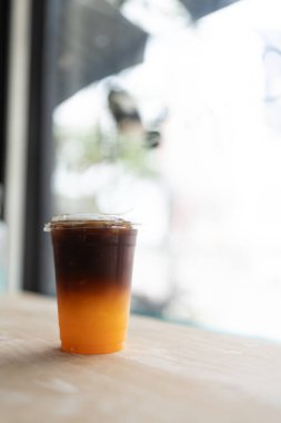 Buzlu kahve ve ahşap masada taze portakal suyu.