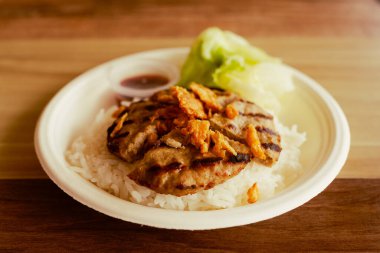 Kağıt tabakta pilavla servis edilen lezzetli hamburger bifteği. Yaratıcı bir füzyon yiyeceği.