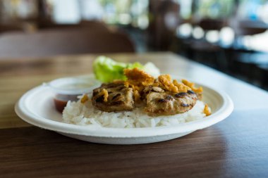 Kağıt tabakta pilavla servis edilen lezzetli hamburger bifteği. Yaratıcı bir füzyon yiyeceği.