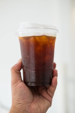 Şeffaf kahve bardağına serpiştirilmiş sade kahve. Plastik kahve bardağını insan elinin üstüne koy.