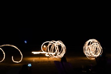 Sahilde sanatçı ateşi jonglörlüğü. İz oluşturmak için açık boya ve uzun pozlama resmi.