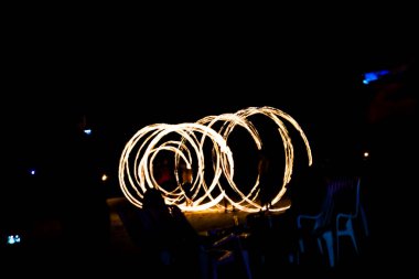 Sahilde sanatçı ateşi jonglörlüğü. İz oluşturmak için açık boya ve uzun pozlama resmi.