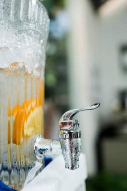 Soğuk aromalı su ve portakallı cam kabın içinde resepsiyon ya da yemek servisi için musluk var..