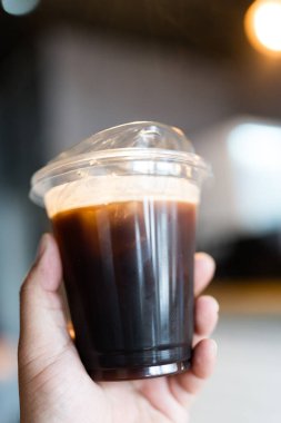 Birisi kafeteryada elinde bir bardak soğuk kahve tutsun..