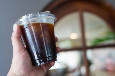 Buzlu, soğuk, sade kahve. Plastik bardağı insan elinin üstüne koy.