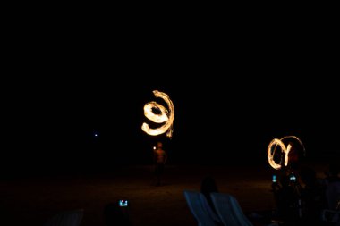 Sahilde ateş bükücüler oynuyor. Sanatçı ateş hokkabazlığı gösterisi