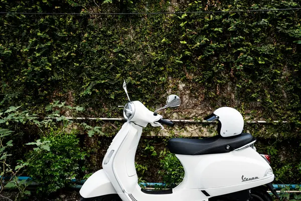 Bangkok, Tayland - 26 Mart 2025: Beyaz Vespa LX125 koltuğun arkasında beyaz kaskla park edilmiş