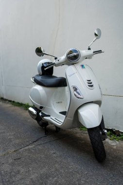 Bangkok, Tayland - 27 Mart 2025: Beyaz Vespa LX125 koltuğun arkasında beyaz kaskla park edilmiş