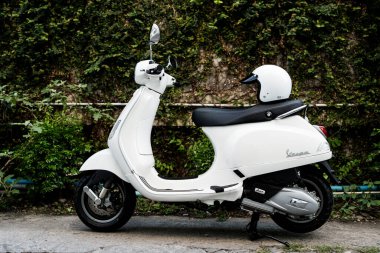 Bangkok, Tayland - 27 Mart 2025: Beyaz Vespa LX125 koltuğun arkasında beyaz kaskla park edilmiş