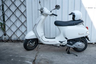 Bangkok, Tayland - 27 Mart 2025: Beyaz Vespa LX125 koltuğun arkasında beyaz kaskla park edilmiş