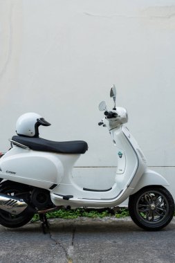 Bangkok, Tayland - 30 Mart 2025: Beyaz Vespa LX125 koltuğun arkasında beyaz kaskla park edilmiş