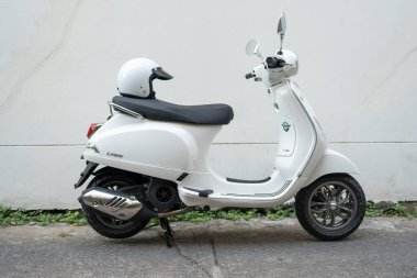 Bangkok, Tayland - 2 Nisan 2025: Beyaz Vespa LX125 park edilmiş ve koltuğun arkasında beyaz Vespa kaskı açık jet suratı var