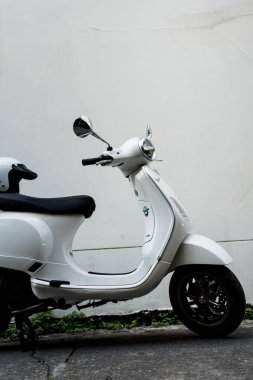 Bangkok, Tayland - 4 Nisan 2025: Beyaz Vespa LX125 koltuğun arkasında beyaz kaskla park edilmiş