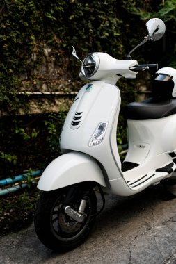 Bangkok, Tayland - 6 Nisan 2025: Beyaz Vespa LX125 koltuğun arkasında beyaz kaskla park edilmiş