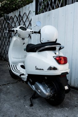 Bangkok, Tayland - 6 Nisan 2025: Beyaz Vespa LX125 beyaz Vespa kaskı açık jet yüzüyle park edilmiş