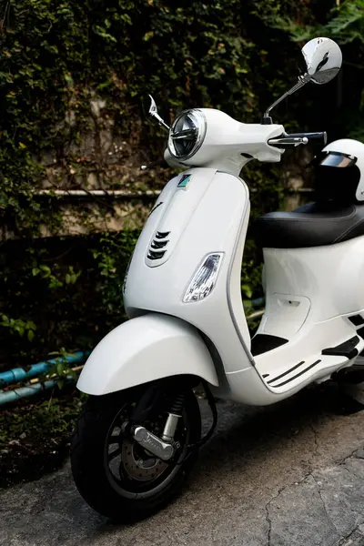 Bangkok, Tayland - 6 Nisan 2025: Beyaz Vespa LX125 koltuğun arkasında beyaz kaskla park edilmiş