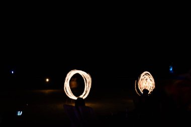 Ateş sanatçıları Tayland sahillerinde gösteri yapıyorlar. İz oluşturmak için açık boya ve uzun pozlama resmi.