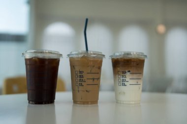 Üçü bir kafe masasında oturmuş buzlu kahve içecekler, buzlu americano, buzlu kahve ve buzlu latte..