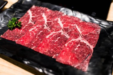 Sukiyaki pişirmek için siyah tepside ince dilimler halinde çiğ et.