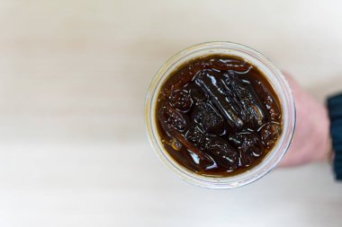 Bir bardak buzlu Americano 'ya el ele tutuşmak. Üst görünüm
