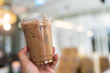 Kafedeki plastik bardakta buzlu mocha ile el ele tutuşmak. Tatlı ve lezzetli buzlu kahve..