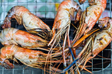 Tay nehri karidesleri kömür ızgarasının üzerinde ızgarada kızartılıyor ve iki tarafı da eşit derecede pişiriliyor. Tayland yemeğinin çok lezzetli bir parçası.