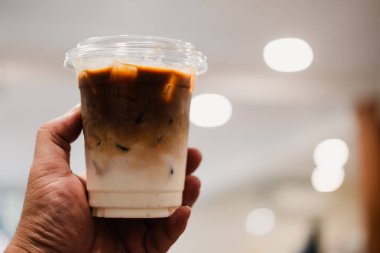 Kahve dükkanında ya da kafede iki katlı bir bardak buzlu latte içerken..