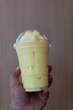 Plastik bardak kapaklı taze portakal suyu içeceği tutan bir el. Lezzetli ve sağlıklı bir içecek. Tatlı içecek..