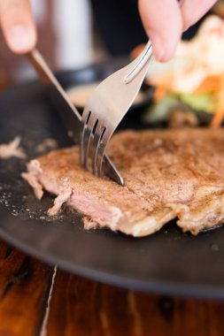 Çatal ve bıçak kullanarak ızgara domuz pirzolası yiyin. Kapat.