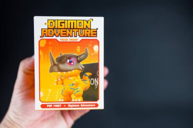 Bangkok, Tayland - 2 Mayıs 2025: Elinde bir kutu oyuncak Digimon Macera Dolapları Serisi figürleri, siyah arka planda pop market.