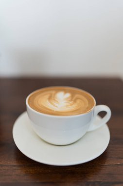 Kafe 'deki ahşap bir masada bir fincan dumanı tüten kahve.