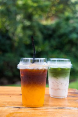 Buzlu Yuzu Americano portakalı ve ahşap masada buzlu kibrit latte yeşil çay.
