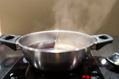 Yin yang sıcak tencere ocağı yemek masasında, iki şişe shabu çorbası.