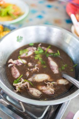 Siyah çorbada bir kase mürekkep balığı. Tayland deniz ürünleri